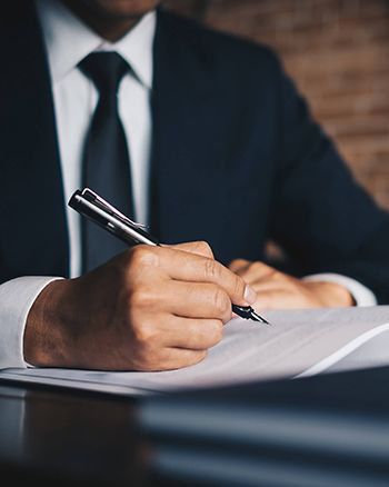 Man in suit writing on a document