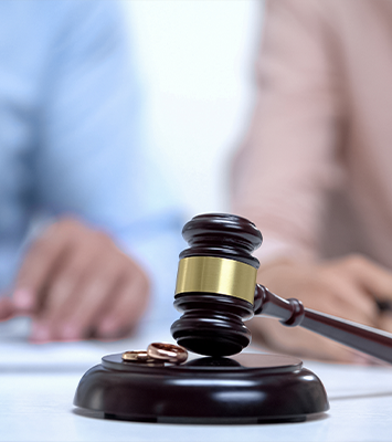 Marriage rings and gavel closeup, spouses signing divorce document