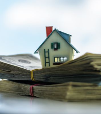 House model on top of bundle of cash