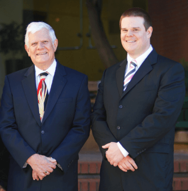Attorneys standing outside wearing suits smiling