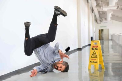 Man falling next to caution wet floor sign