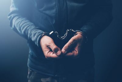 Close up of man in black sweatshirt with hands in handcuffs