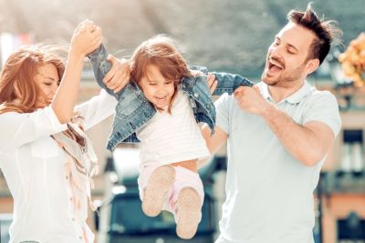 Man and woman lifting smiling child by her arms