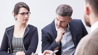 Man and woman sitting across man with a clipboard