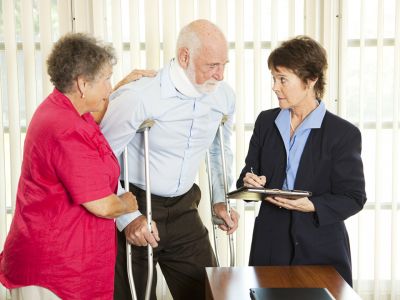 Elderly couple, man on crutches, talking to a woman in a suit