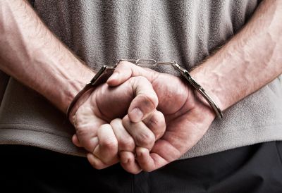 close up of man's hands behind his back in handcuffs