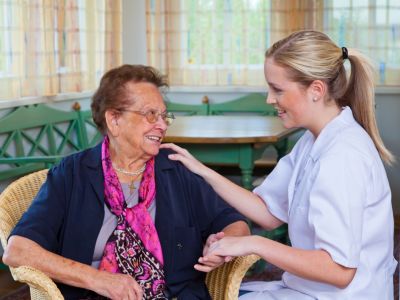 Young blonde woman touching shoulder and holding hand of older woman