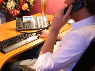 Man on the phone with hand on a mouse sitting at desk with keyboard