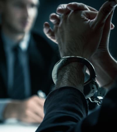 Criminal man with handcuffs in interrogation room