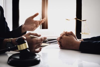 two people meeting with gavel and scales of justice on table