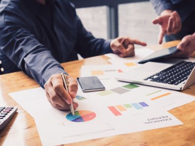 Man sitting at desk pointing to a colorful pie chart with a pen