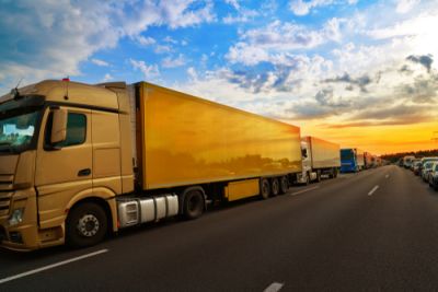 Several yellow semi trucks in a row on a road