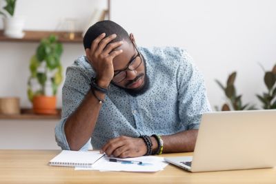 Man with hand on his head looking at laptop 