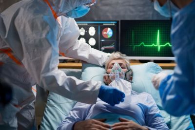 Woman on a hospital bed with mask being held up to her face 