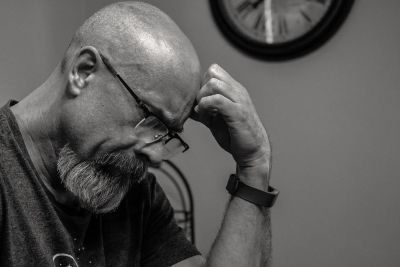 Man looking down with hand on his head 