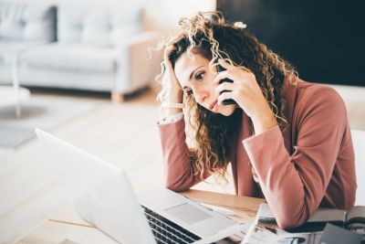 Woman on phone looking at laptop