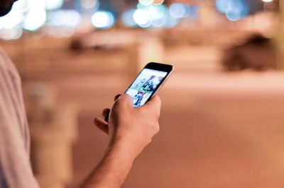 Person scrolling through their phone with a street in the background