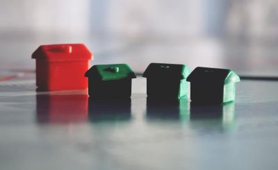 Tiny toy red house with three smaller toy green houses to its right