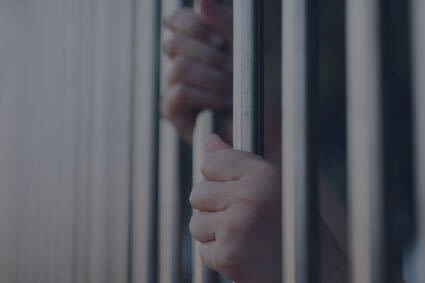 Hands gripping jail cell bars