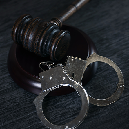 Handcuffs and gavel on dark rustic table