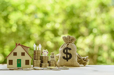 Money bag and coins lined up next to a toy house