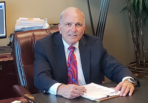 john campbell sitting at his desk with papers in his hand
