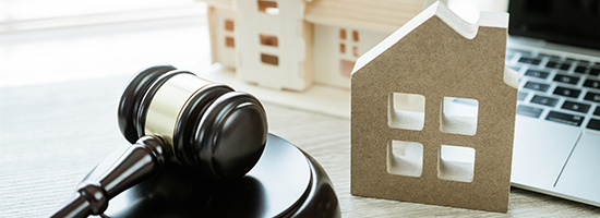 A cardboard house cutout with a gavel and laptop next to it