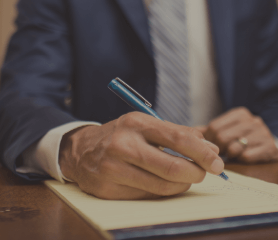 Man in Blue Suit Writing on Notepad
