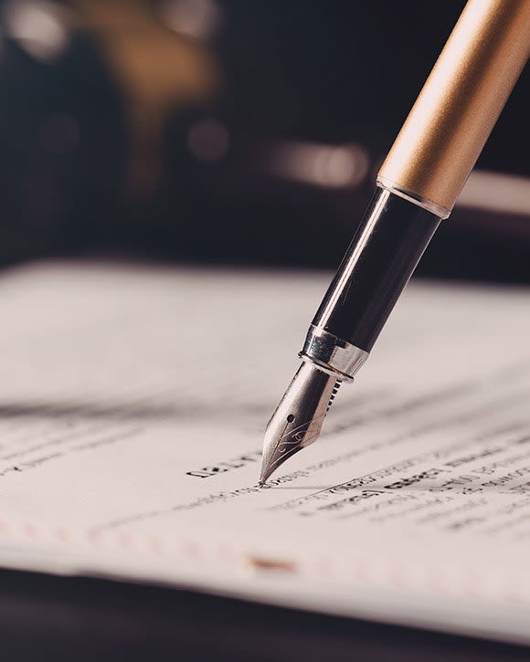 Old fashioned ink pen signing a piece of paper