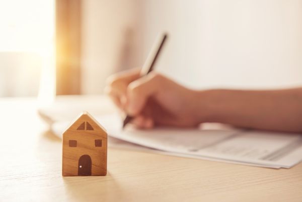 Small Wooden home in front of a document being filled out