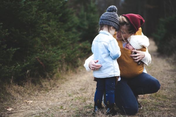 Mother holding her two children in the woods