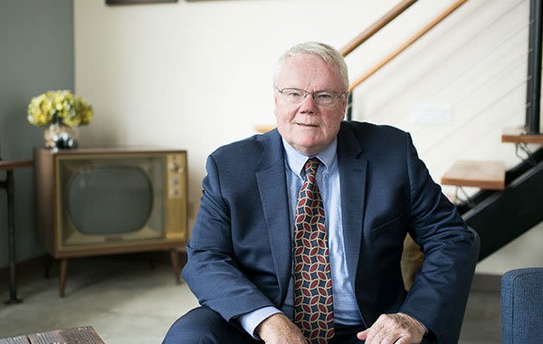 Attorney John McAvoy in suit sitting in chair