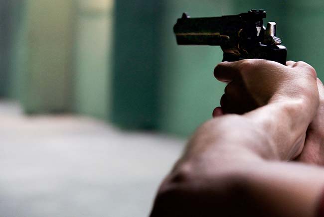 Man holding up a gun to shoot