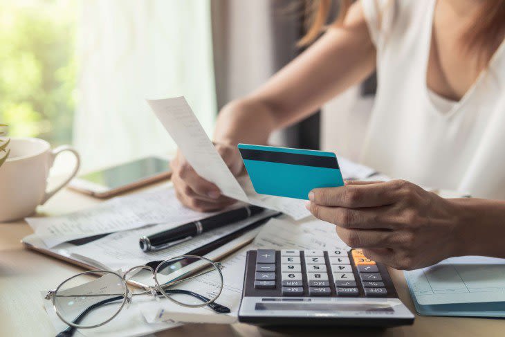 Woman making calculations holding a receipt and a credit card