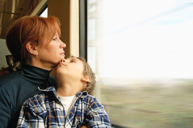 Woman with son on her lap as she looks out train window