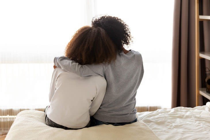Mother hugging daughter on bed