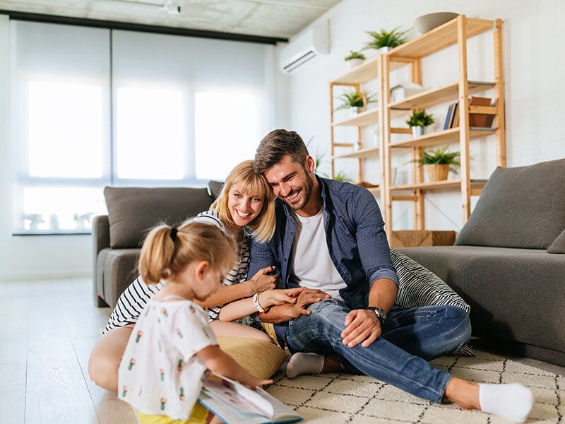 Happy parents watching their daughter play with a book