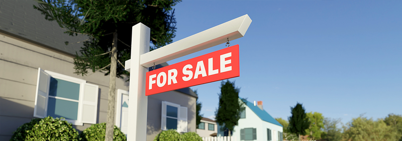 Real estate sign in front of a house for sale in a nice suburban neighborhood.