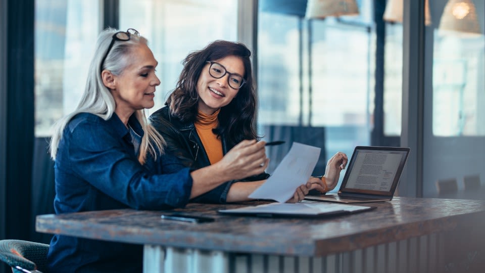 Two professionals sitting at a table together reviewing a document