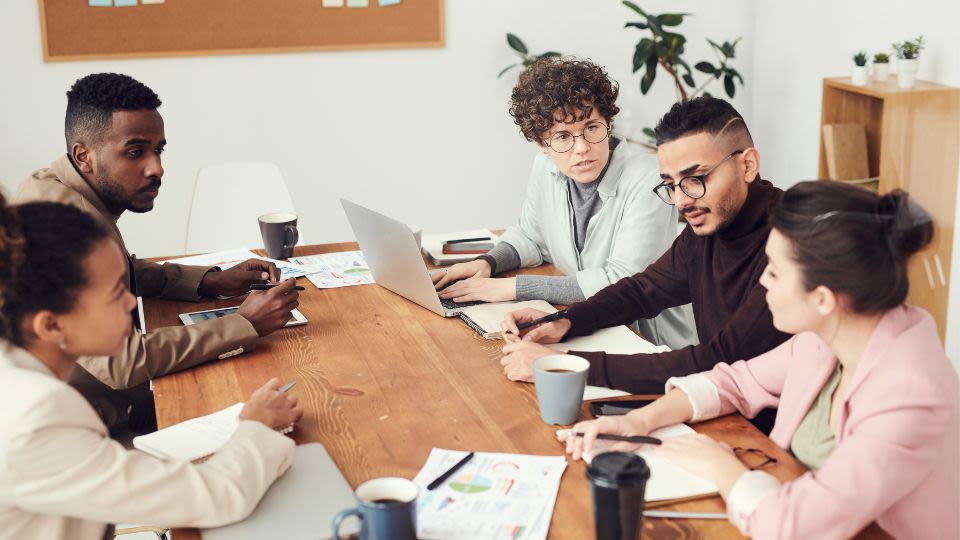 A group of business professionals sitting around a conference table talking
