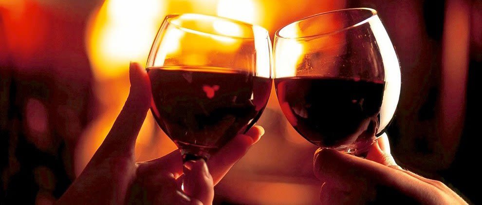 Two people with red wine clinking