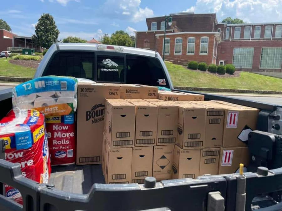 Pickup truck bed loaded with Bounty paper napkins, Charmin toilet paper, and other paper goods donations