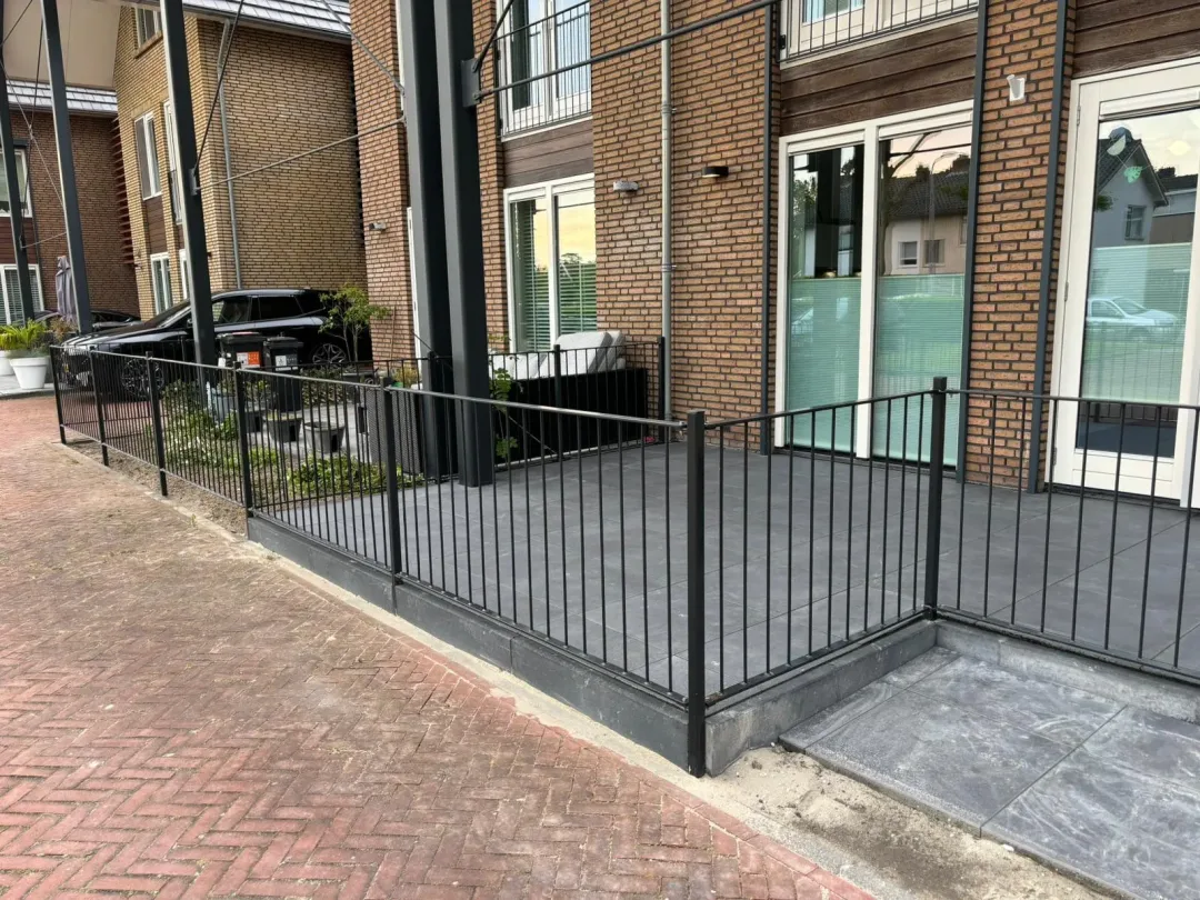 Stalen hekwerk aan een terras voor een huis vanaf de voorkant