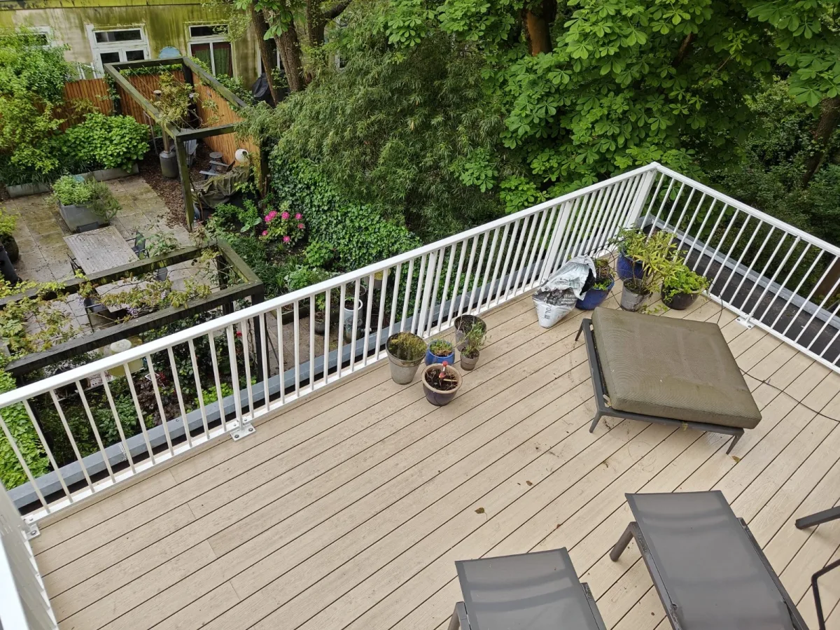 Dit is het aluminium hek ASH-3015 met een witte RAL kleur op een balkon vanaf boven met houten vlonders