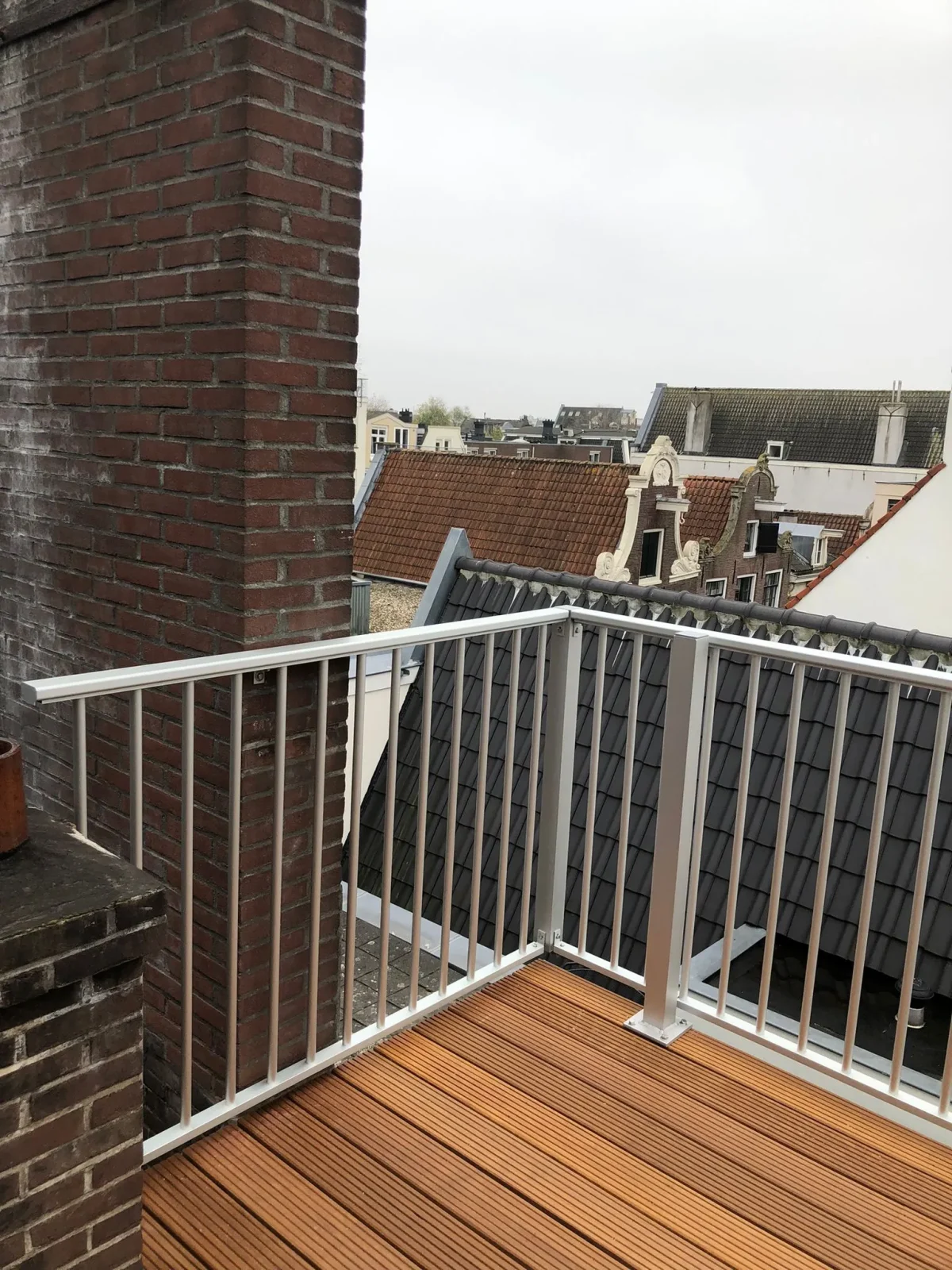 Dit is de linker hoek van het aluminium hek ASH-R25 zilver kleurig gezien vanaf het balkon