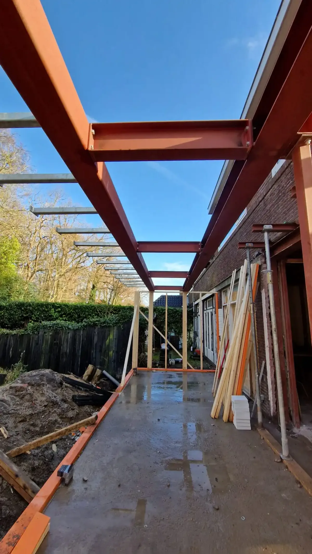 Metalen construcie voor een aanbouw aan de achterkant van een huis vanaf rechts gefotografeerd