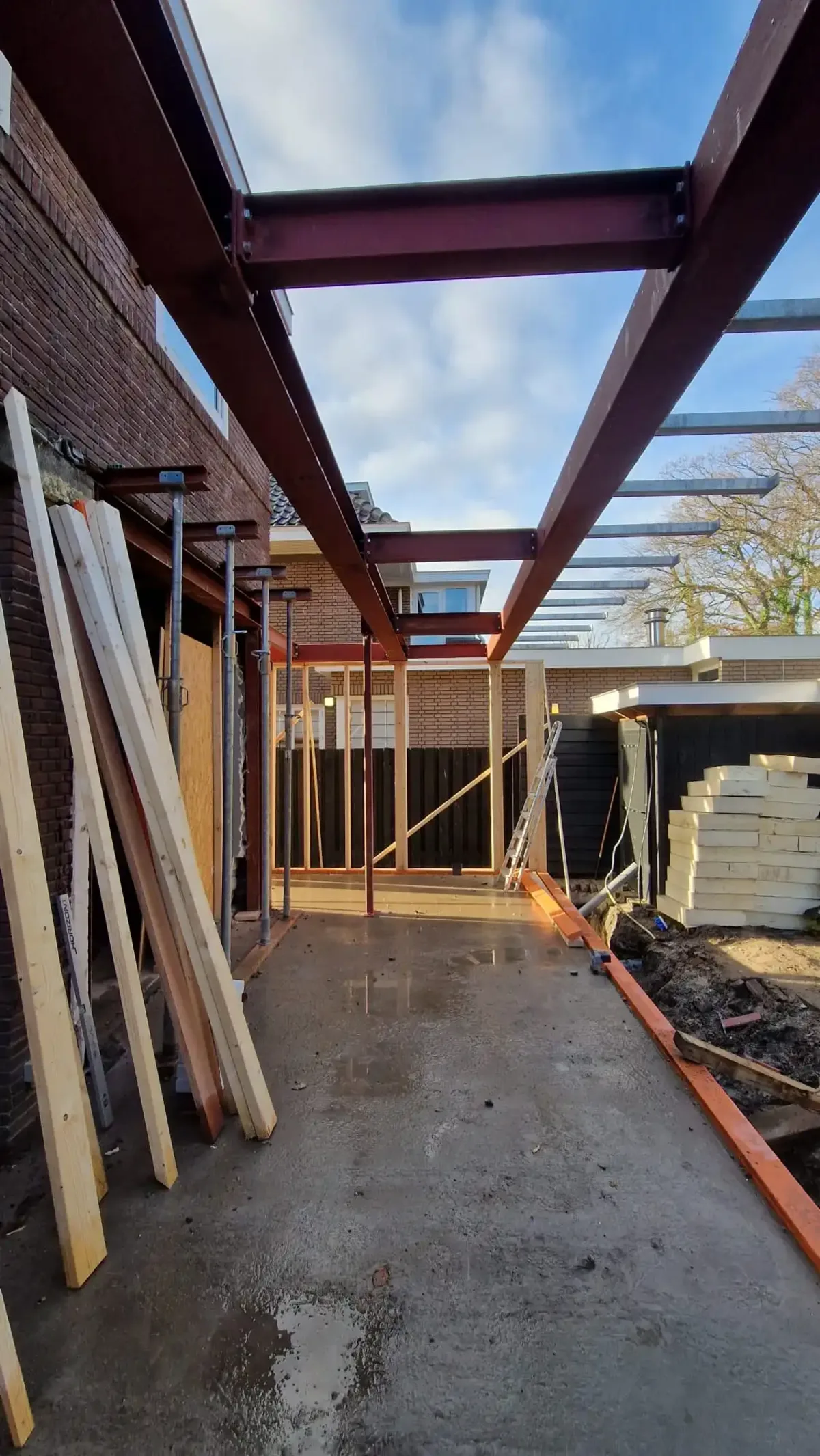 Metalen constructie voor een aanbouw aan de achterkant van een huis vanaf links gefotografeerd