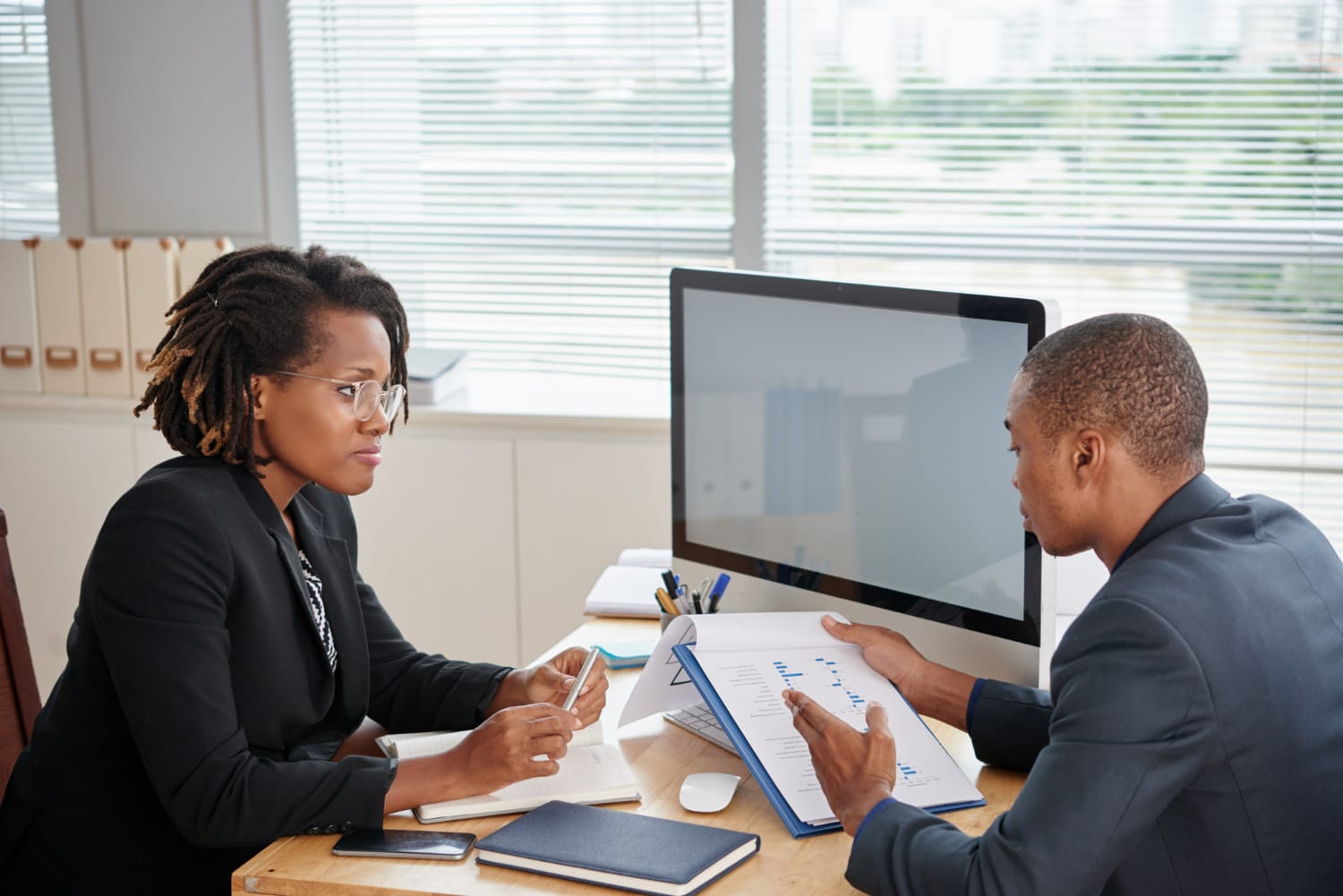 Two professionals discussing work over a computer