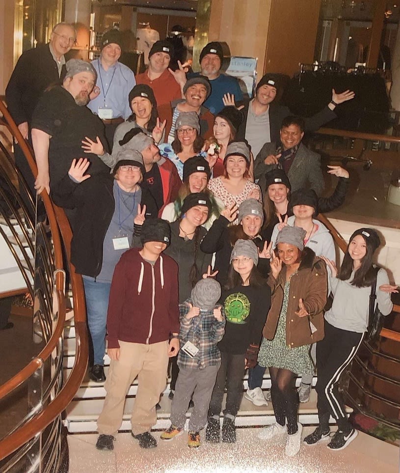 a bunch of people the stairs making silly faces and all wearing warm hats