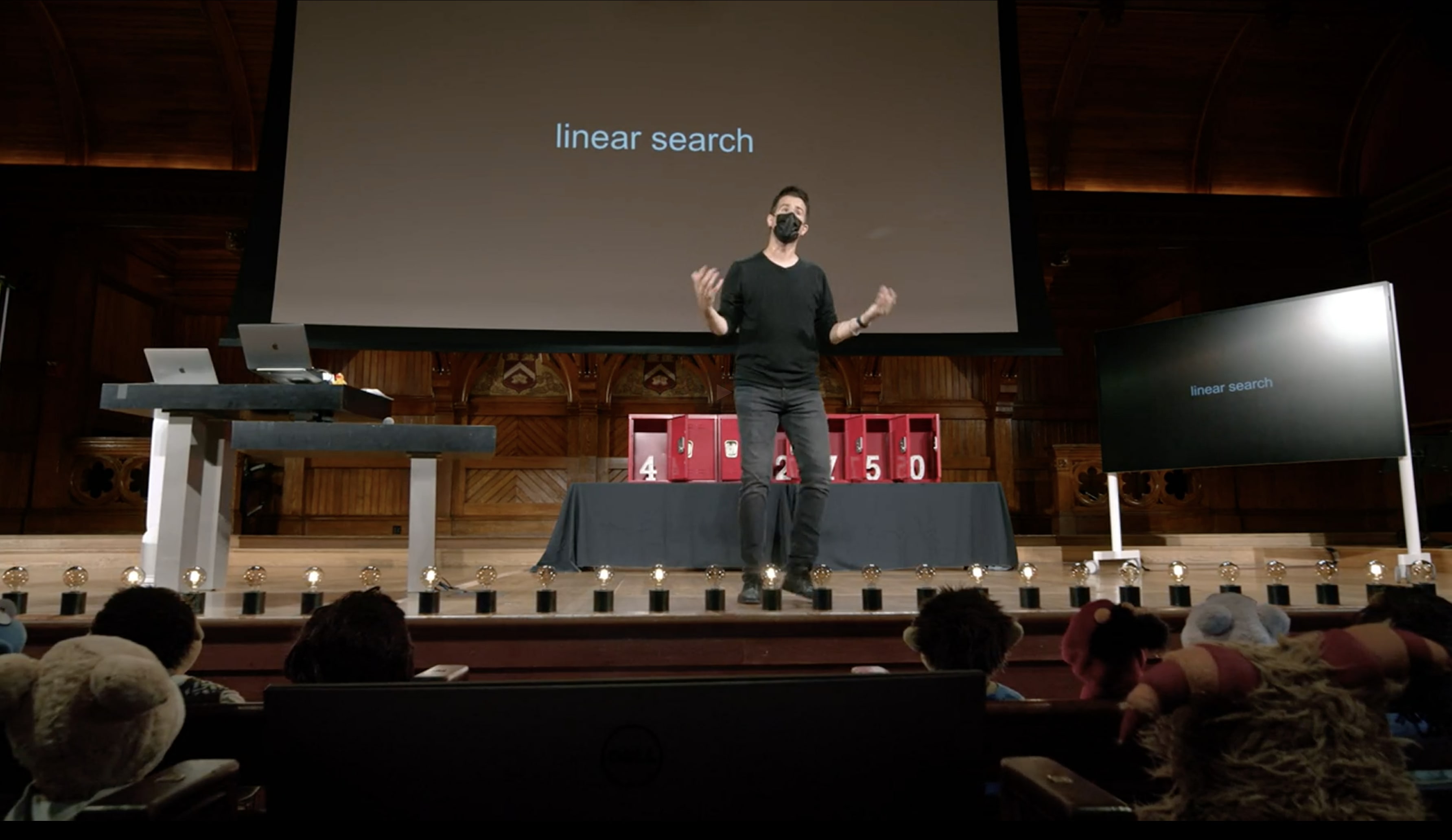 David J. Malan on stage at Harvard teaching Linear Search using lockers and numbers